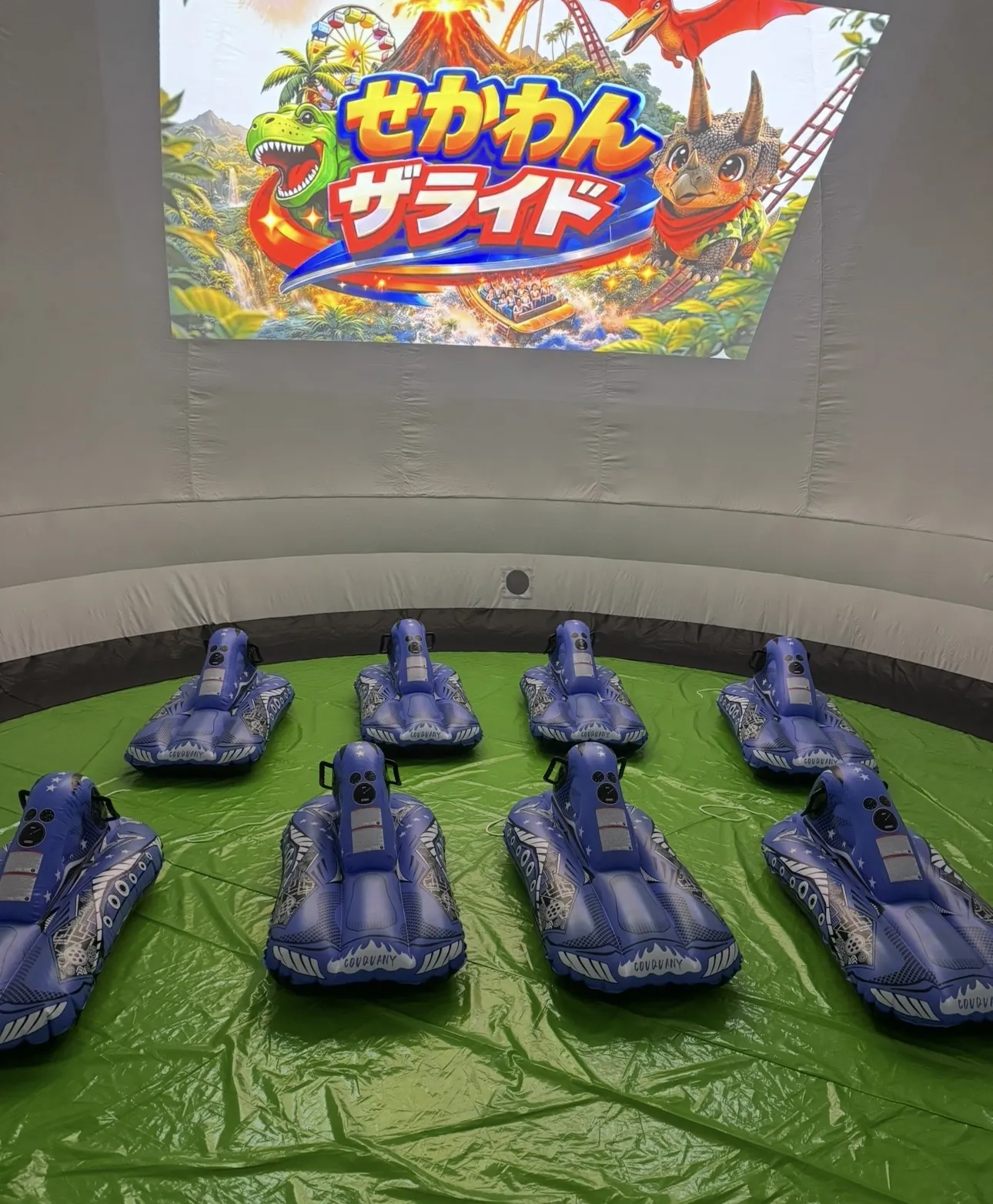 ドームテントの中に並べられた8艇のゴムボートと、正面のスクリーン